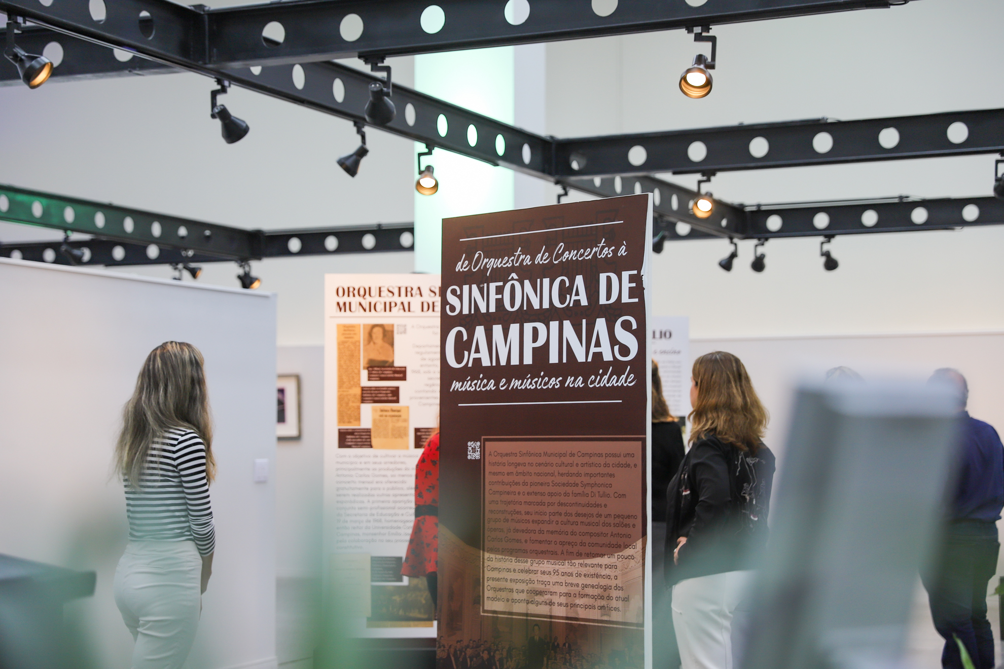 imagem geral da exposição, com os painéis informativos sendo observado pelas pessoas