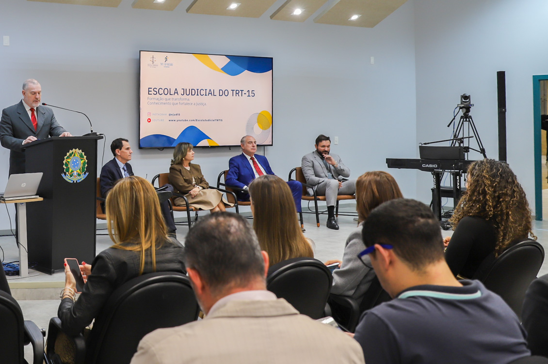 imagem mostra a mesa de abertura do seminário ao fundo, o mestre de cerimônias no púlpito, sendo observados pela plateia.