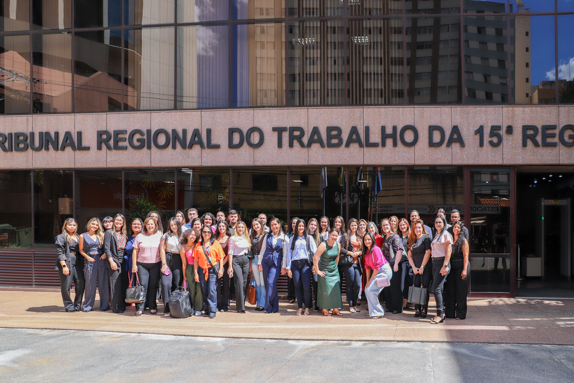 Estudantes e professores estão em pé em frente ao prédio do TRT-15