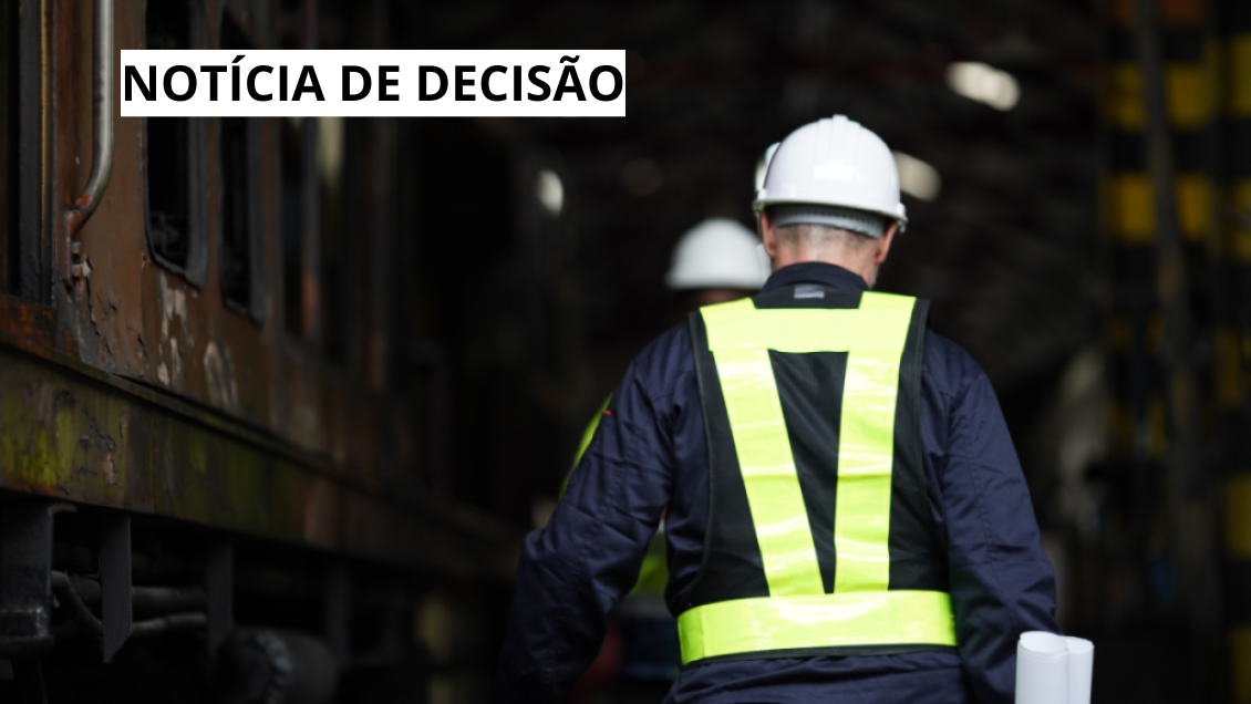 Banner retrata um empregado usando EPIs andando de costa entre duas locomotivas